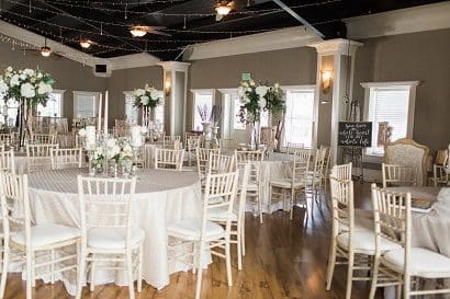 Ballroom wedding set-up, champagne colored linens, white chivaris, draping lights on the ceiling and sequined bistro tables.