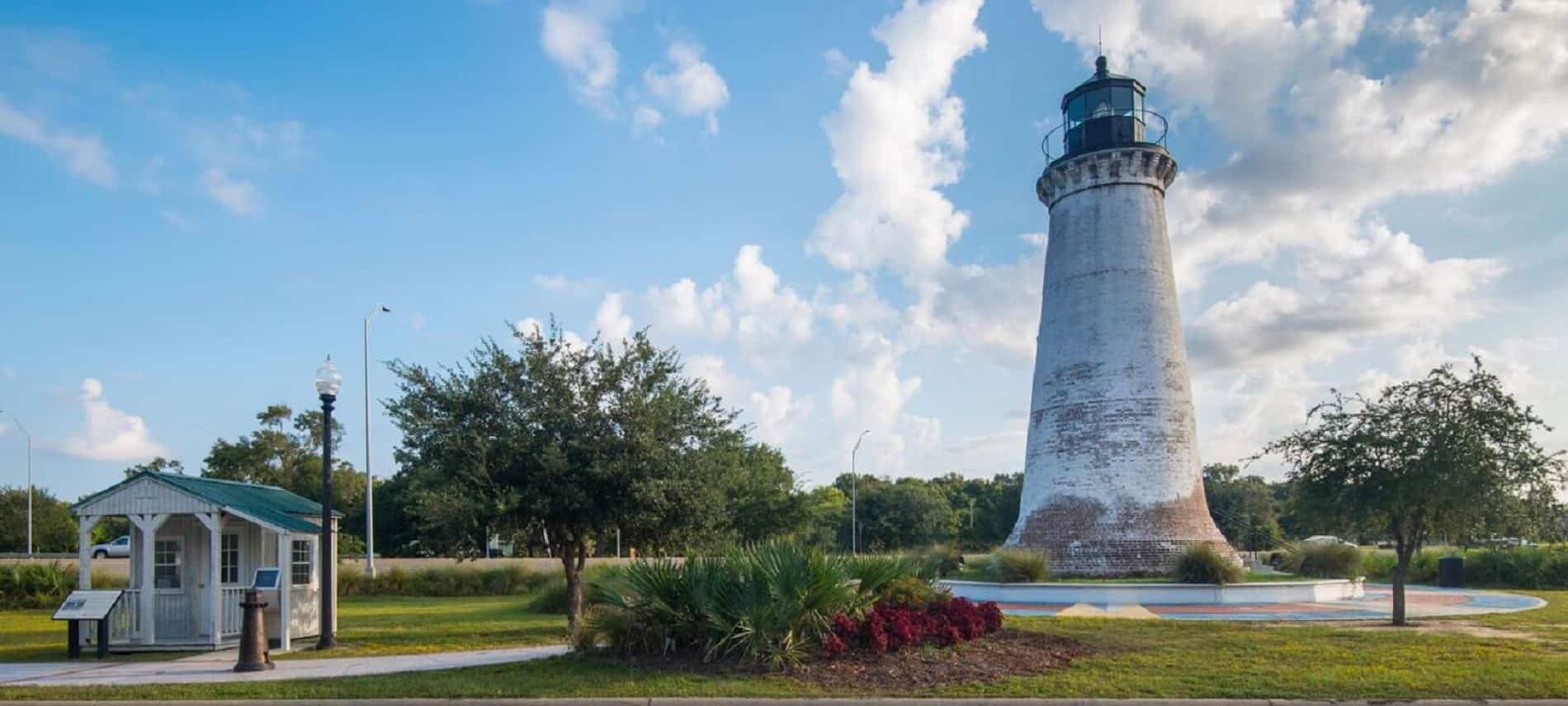1859 Round Island lighthouse rescued from Mississippi Sound after Hurricane Katrina and relocated, surrounded by trees, grass and blue skies