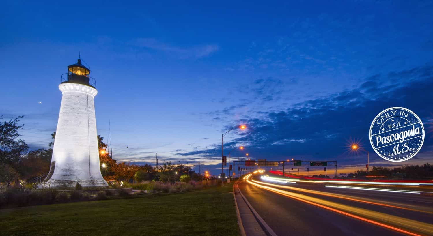 White Round Island Lighthouse at dusk in its new location with blurry street and car lights