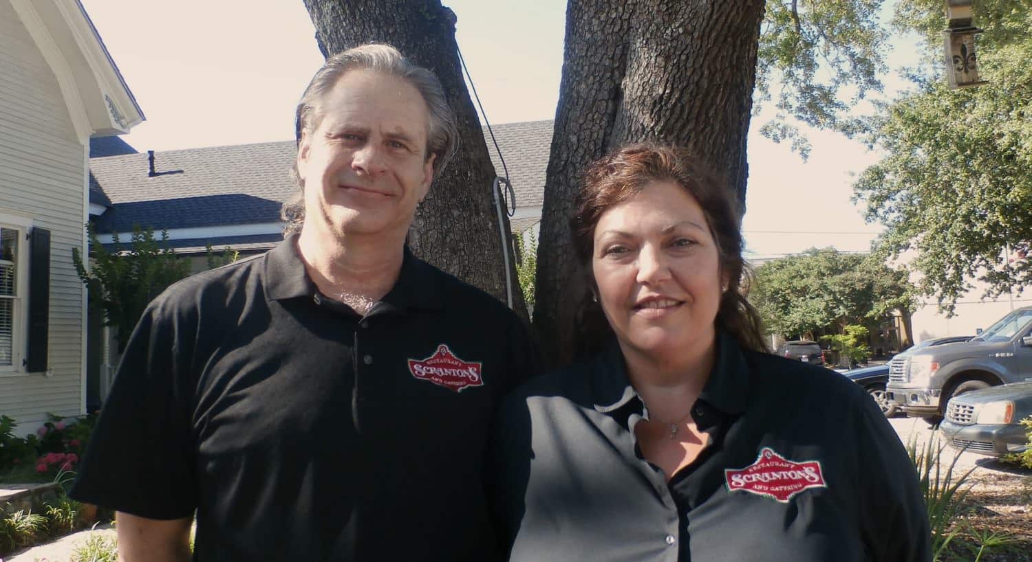 Man and woman with Scranton's Restaurant shirts standing in front of a tree