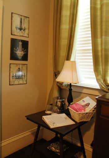 Charleston guest room corner - window with gold curtains and ivory blinds, small table with lamp, ice bucket, glasses and magazines