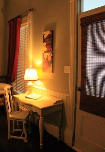 Little Gem guest room with window, exterior door, and white desk with lamp and chair